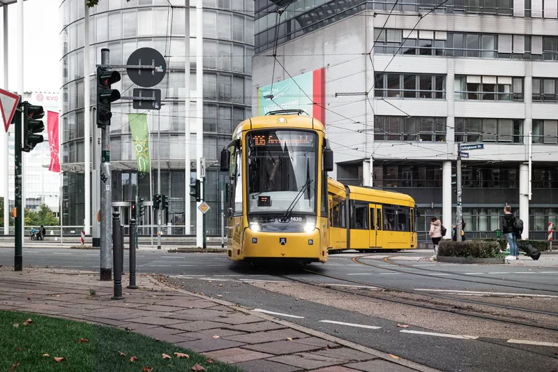 Moderne gelbe Straßenbahn der Linie 106 der Ruhrbahn in Essen vor zeitgenössischer Glasarchitektur - ein Symbol für nachhaltigen öffentlichen Nahverkehr im Ruhrgebiet.

