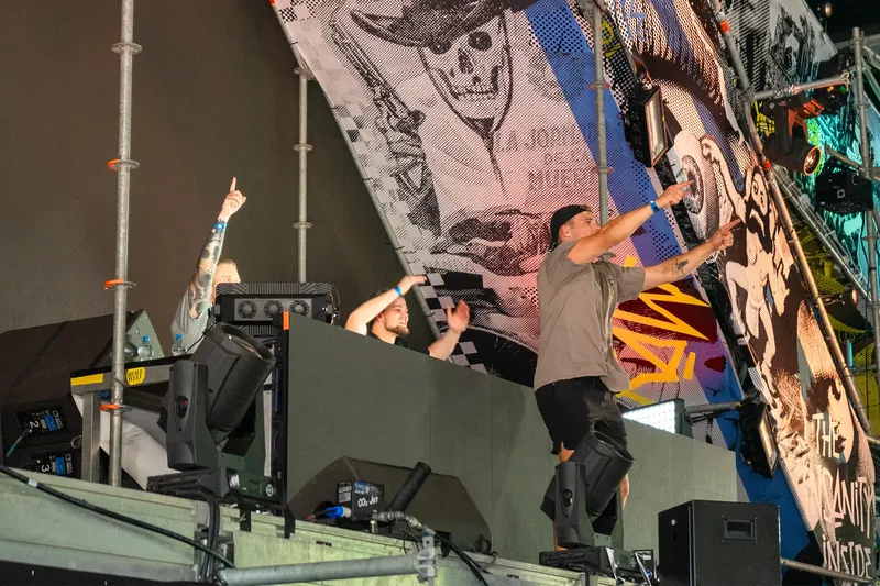 Energiegeladene Live-Performance eines DJ-Duos auf einer Bühne mit beeindruckender visueller Kulisse. Dynamische Nachtclub-Atmosphäre mit großformatiger LED-Wand, die abstrakte Kunst und Grafiken zeigt. Professionelle Eventfotografie in hoher Auflösung (1536x1024) im RGB-Format.
