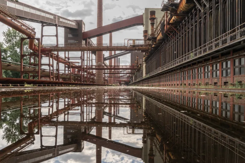 Industriedenkmal Zeche Zollverein Essen, imposante Förderanlagen und Schornsteine spiegeln sich im Wasser, Industriearchitektur im Ruhrgebiet, UNESCO-Welterbe
