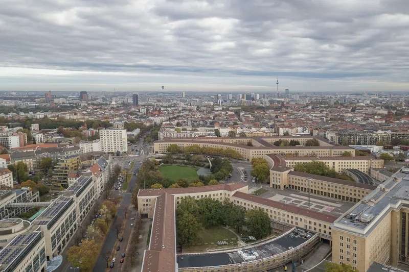 Atemberaubende Luftaufnahme des historischen Tempelhofer Feldes in Berlin: Imposante Architektur des ehemaligen Flughafengebäudes, urbane Parklandschaft und Berliner Skyline mit Fernsehturm. Perfekte Kombination aus Geschichte und modernem Stadtleben.
