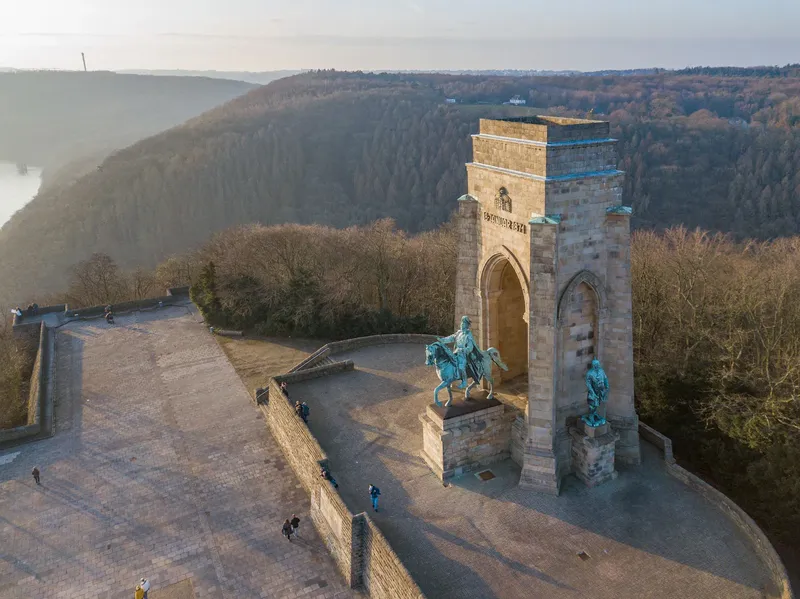 Das monumentale Kaiser-Wilhelm-Denkmal auf der Hohensyburg in Dortmund: Ein 34 Meter hoher historischer Turm mit Reiterstandbild Kaiser Wilhelms I., flankiert von Bismarck und Moltke, bietet atemberaubende Panoramablicke über das Ruhrtal und den Hengsteysee. Erbaut 1902, ist es heute ein beliebtes Ausflugsziel und bedeutendes Nationaldenkmal.
