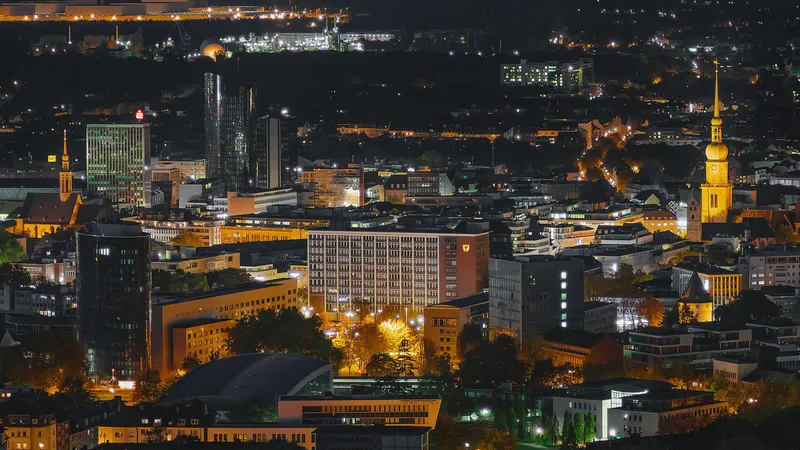 Atemberaubende Nachtaufnahme der Dortmunder Skyline mit beleuchteten Hochhäusern, historischen Kirchtürmen und modernen Geschäftsgebäuden. Ein beeindruckendes Stadtpanorama, das die perfekte Symbiose zwischen Tradition und Moderne der Ruhrgebietsmetropole zeigt.
