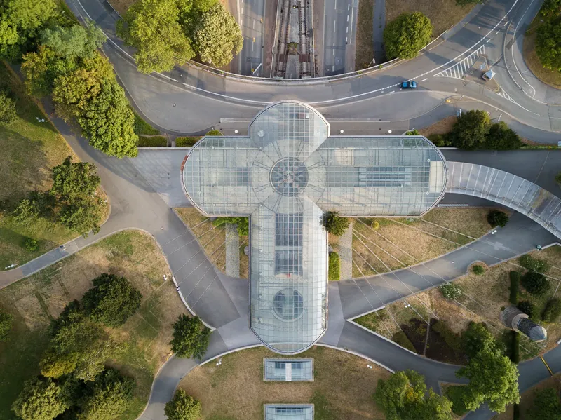 Eindrucksvolle Luftaufnahme der U-Bahn-Station Westfalenhalle in Dortmund mit charakteristischer kreuzförmiger Glasarchitektur, modernem Design und perfekter Verkehrsanbindung. Die Station verbindet öffentlichen Nahverkehr mit zeitgenössischer Architektur.
