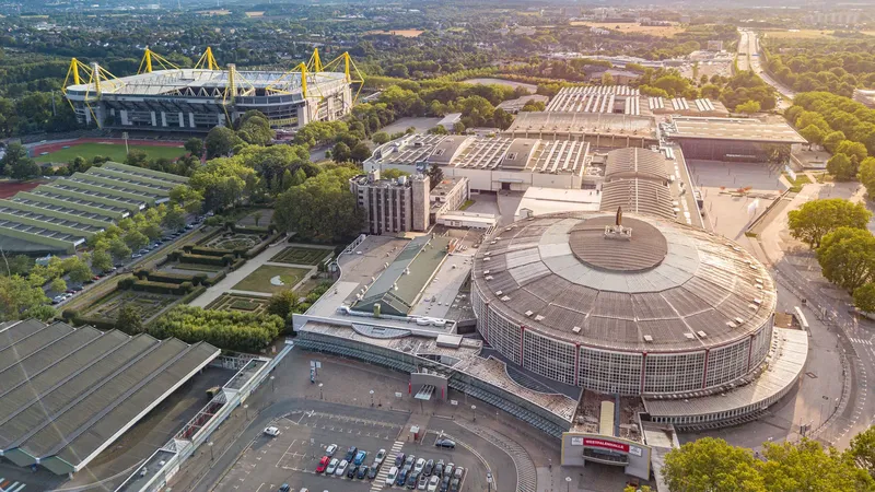 Luftaufnahme des Dortmunder Sportzentrums mit Signal Iduna Park und Westfalenhalle - Deutschlands größtes Fußballstadion und die historische Veranstaltungshalle in beeindruckender Drohnenperspektive. Perfekte Darstellung der modernen Sportinfrastruktur im Ruhrgebiet.
