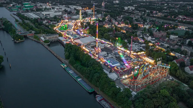Atemberaubende Luftaufnahme der Cranger Kirmes bei Nacht - Deutschlands größtes Volksfest präsentiert sich mit spektakulär beleuchteten Fahrgeschäften, Achterbahnen und einem lebendigen Festgelände entlang des Rhein-Herne-Kanals im Herzen des Ruhrgebiets.
