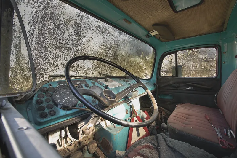 Atmosphärisches Foto eines verlassenen Vintage-LKW Innenraums in Türkis mit originalem Armaturenbrett, rundem Tachometer und patinierter Ledersitzbank. Authentische Urbex-Fotografie in hoher Auflösung (1536x1024) zeigt die zeitlose Schönheit vergangener Automobilgeschichte.
