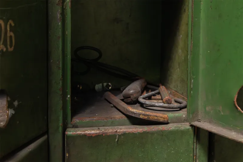 Verrostete alte Werkzeuge in geöffnetem grünen Metallschrank
