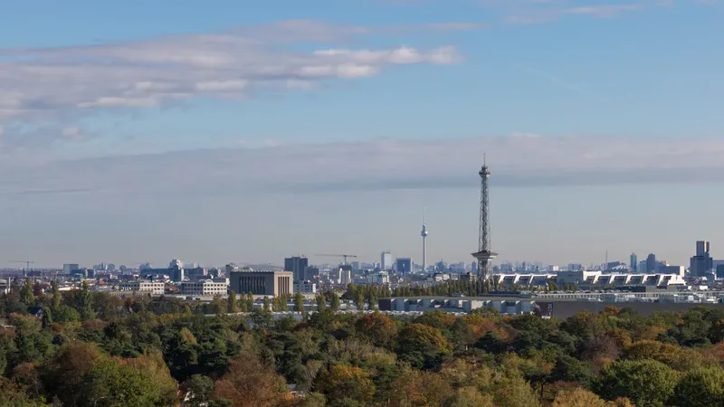 Atemberaubender Panoramablick vom Teufelsberg über Berlin mit Fernsehturm und Funkturm, eingebettet in herbstliche Waldlandschaft. Perfekte Aussicht auf die Hauptstadt-Skyline bei klarem Himmel - ein einzigartiger Perspektivwechsel über der Metropole.
